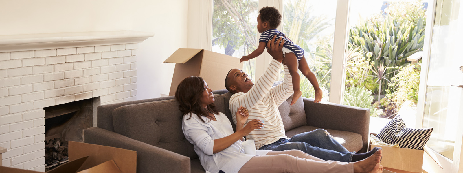 familia en una sala de estar jugando y sujetando a un niño en alto